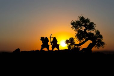 Düelloda tree yakınındaki iki samurais silüeti. İki samurais ve günbatımı gökyüzü ile hayal et. Seçici odak