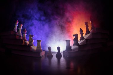 İş hiyerarşisi. Satranç taşları ile strateji kavramı. Kralın üst bir piramit kitapların üzerinde dururken satranç. Tonda ışık ile karanlık sisli arka plan. Kopya alanı.