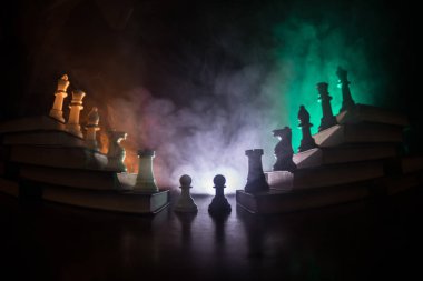 İş hiyerarşisi. Satranç taşları ile strateji kavramı. Kralın üst bir piramit kitapların üzerinde dururken satranç. Tonda ışık ile karanlık sisli arka plan. Kopya alanı.
