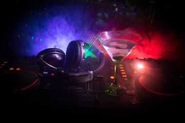 Martini gece kulübünde dj denetleyicisinde içinde zeytin ile bardak. Club içki müzik parti disko ışıkları ile gece kulübünde DJ konsolu.