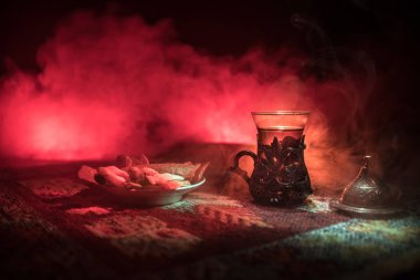 Cam bir halı ile ışık ve duman koyu arka plan üzerinde Doğu snacks ile Arap tea. Doğu çay kavramı. Boş alanı. Seçici odak.