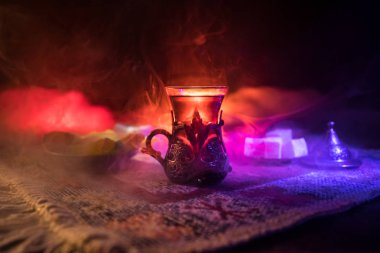Cam bir halı ile ışık ve duman koyu arka plan üzerinde Doğu snacks ile Arap tea. Doğu çay kavramı. Boş alanı. Seçici odak.