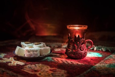 Cam bir halı ile ışık ve duman koyu arka plan üzerinde Doğu snacks ile Arap tea. Doğu çay kavramı. Boş alanı. Seçici odak.