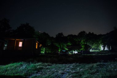 Binanın Orman geceleri ay veya vintage kır evi ile bulutlar ve yıldız ile gece dağ gece manzarası. Yaz gecesi. Uzun pozlama ile çekilen fotoğraf