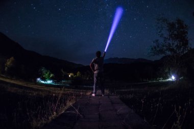 Adam gece ormanda silüeti. Işık ile karanlık ormanın içinde duran kişi silüeti. Karanlık gece ormanda. Gerçeküstü gece orman sahne. Korku Cadılar Bayramı kavramı.