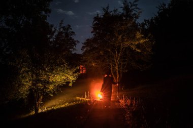 Adam gece ormanda silüeti. Işık ile karanlık ormanın içinde duran kişi silüeti. Karanlık gece ormanda. Gerçeküstü gece orman sahne. Korku Cadılar Bayramı kavramı.