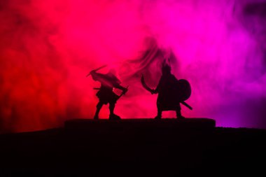 Düelloda iki Ortaçağ savaşçıları silüeti. Karanlık kılıçla ile iki savaşçı resimle sisli arka plan tonda. Seçici odak.