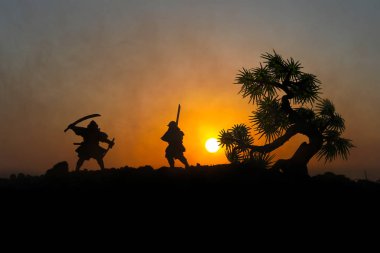 Düelloda tree yakınındaki iki samurais silüeti. İki samurais ve günbatımı gökyüzü ile hayal et. Seçici odak
