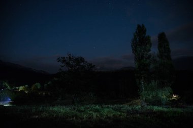 Yıldızlı gece dağlar ve orman ile güzel gece manzarası. Gece orman yeşil çayır ve dağ parlak yıldızlı gece veya görünümünde Samanyolu