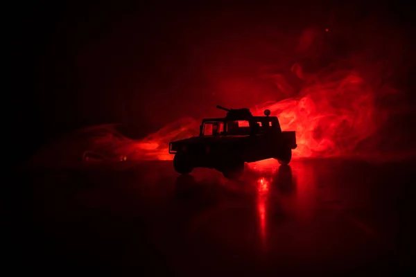 Military patrol car on dark toned foggy background. Army war concept. Silhouette of armored vehicle with gun in action. Decorated. Selective focus