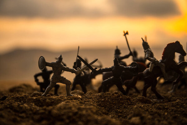Средневековая боевая сцена с кавалерией и пехотой. Силуэты фигур как отдельные объекты, борьба между воинами на закатном туманном фоне. Селективный фокус
