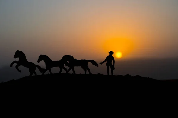 牛仔概念 牛仔与马在日落时间的剪影 山上有黄色天空的牛仔剪影 选择性聚焦 — 图库照片