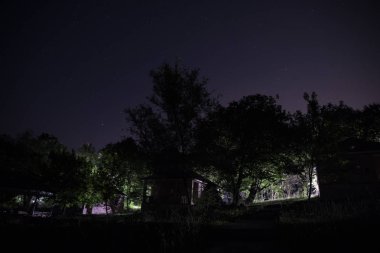 Binanın Orman geceleri ay veya vintage kır evi ile bulutlar ve yıldız ile gece dağ gece manzarası. Yaz gecesi. Uzun pozlama ile çekilen fotoğraf