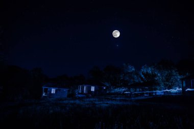 Binanın Orman geceleri ay veya vintage kır evi ile bulutlar ve yıldız ile gece dağ gece manzarası. Yaz gecesi. Uzun pozlama ile çekilen fotoğraf