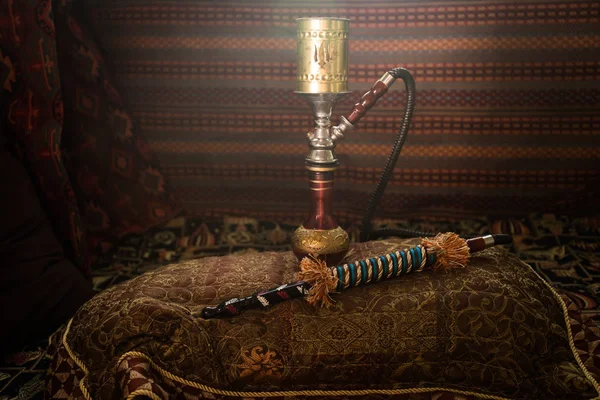 Hookah hot coals on shisha bowl making clouds of steam at Arabian interior. Oriental ornament on the carpet. Stylish oriental shisha with backlight. For Shisha advertisement. Selective focus