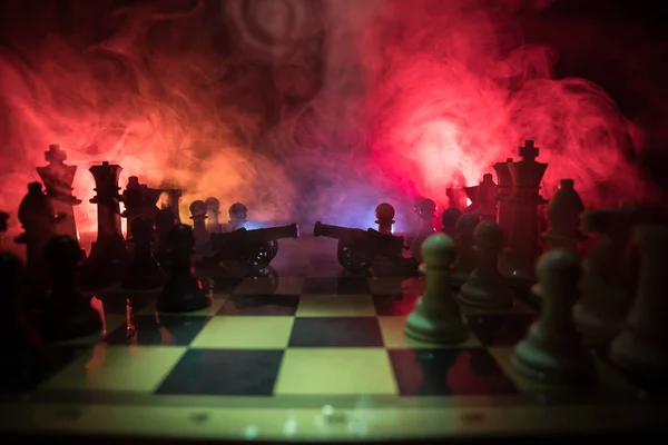 Medieval battle scene with two cannon on chessboard. Chess board game concept of business ideas and competition and strategy ideas Chess figures on a dark background with smoke and fog.