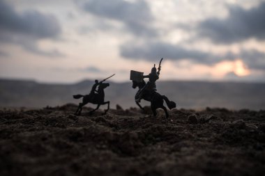 Süvari ve piyade ile ortaçağ savaş sahnesi. Siluetleri şekiller ayrı nesneler olarak mücadele günbatımı sisli arka plan savaşçılar arasında. Seçici odak