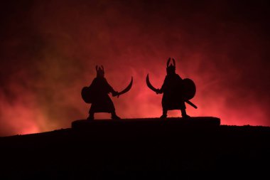 Düelloda iki Ortaçağ savaşçıları silüeti. Karanlık kılıçla ile iki savaşçı resimle sisli arka plan tonda. Seçici odak.