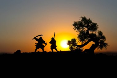 Düelloda tree yakınındaki iki samurais silüeti. İki samurais ve günbatımı gökyüzü ile hayal et. Seçici odak