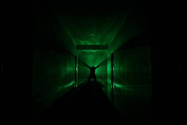 Ürpertici siluet koyu terk edilmiş binada. Manyak genel kavram ya da kabine kapılar ile karanlık koridor ve ışıkları ile farklı pozlar duran korkunç korku kişi silueti ile ilgili korku.