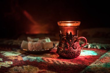 Cam bir halı ile ışık ve duman koyu arka plan üzerinde Doğu snacks ile Arap tea. Doğu çay kavramı. Boş alanı. Seçici odak.