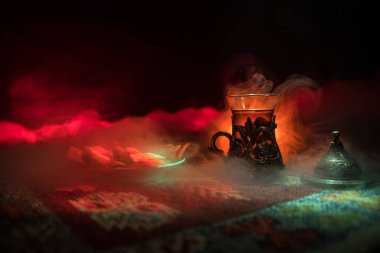 Cam bir halı ile ışık ve duman koyu arka plan üzerinde Doğu snacks ile Arap tea. Doğu çay kavramı. Boş alanı. Seçici odak.