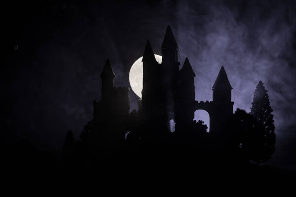 Mysterious medieval castle in a misty full moon. Abandoned gothic style old castle at night. Selective focus