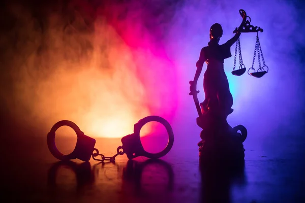 法的な法律概念 霧の背景に赤と青の警察ライトが点滅と裏側に正義の女神像と手錠のシルエット 選択と集中 — ストック写真