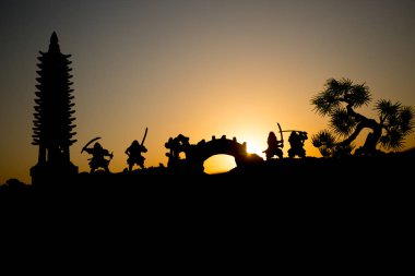 Savaşçı bir kılıç siluet bir gökyüzü ninja ile. Samuray koyu tonda sisli arka plan ile dağın zirvesinde. Seçici odak