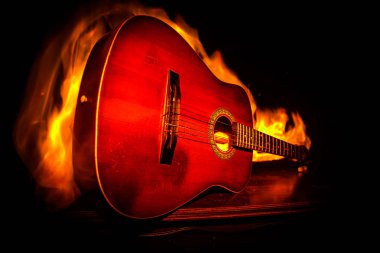 Müzik konsepti. Akustik gitar ile kopya alanı dumanla ışık demeti altında karanlık bir arka plan üzerinde. Gitar patlayan. Etkileri ateş. Gerçeküstü gitar. Seçici odak