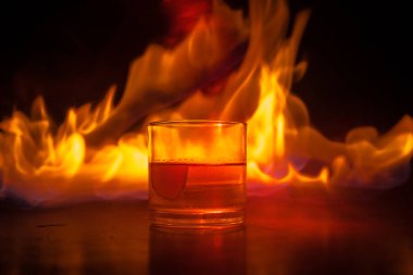 Yangın kavramı içine viski. Bardak viski ve buz ile renk ışık ahşap yüzeyde ve sis arka plan üzerinde. Yakın çekim. Seçici odak