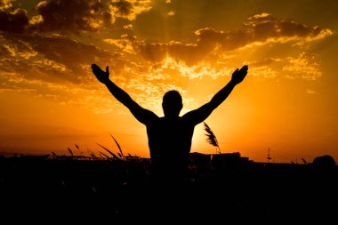 Günbatımında kendi elleriyle adam silüeti.