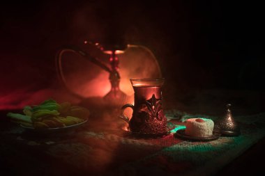 Nargile kömürü nargile kupa Arap iç de buhar bulutları yapma. Şark süsleme halı Doğu çay töreni üzerinde. Şık oryantal shisha içinde karanlık arka ışık ile. Seçici odak