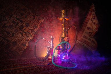 Hookah hot coals on shisha bowl making clouds of steam at Arabian interior. Oriental ornament on the carpet. Stylish oriental shisha in dark with backlight. For Shisha advertisement. Selective focus clipart
