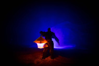 Yağmurluk ile onun el kavramı içinde parlayan fener karanlık ormanın gelen adam. Lamba korku katille silüeti. Dekorasyon