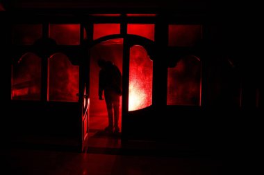 Kapalı cam bir kapıdan geçen, bilinmeyen bir gölge figürünün silueti. Geceleri pencerenin önündeki bir insanın silueti. Manyağın bulanık silueti korkunç cadılar bayramı konsepti.