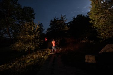 Adam gece ormanda silüeti. Işık ile karanlık ormanın içinde duran kişi silüeti. Karanlık gece ormanda. Gerçeküstü gece orman sahne. Korku Cadılar Bayramı kavramı.