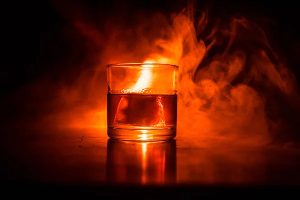 火の概念でウイスキー ウィスキーの色光と木の表面の氷と霧の背景にガラス クローズ アップ 選択と集中 — ストック写真