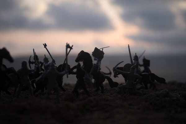 Средневековая боевая сцена с кавалерией и пехотой. Силуэты фигур как отдельные объекты, борьба между воинами на закатном туманном фоне. Селективный фокус
