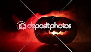 Kaymak vurdu. Korkunç Halloween kabak oyma gözleri ve yangın ve sis karanlık bir arka plan üzerinde mum içinde yanma ile bir gülümseme ile. Boş alanı. Seçici odak