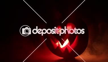 Kaymak vurdu. Korkunç Halloween kabak oyma gözleri ve yangın ve sis karanlık bir arka plan üzerinde mum içinde yanma ile bir gülümseme ile. Boş alanı. Seçici odak