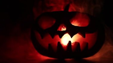 Kaymak vurdu. Korkunç Halloween kabak oyma gözleri ve yangın ve sis karanlık bir arka plan üzerinde mum içinde yanma ile bir gülümseme ile. Boş alanı. Seçici odak