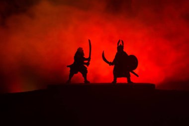 Düelloda iki Ortaçağ savaşçıları silüeti. Karanlık kılıçla ile iki savaşçı resimle sisli arka plan tonda. Seçici odak.