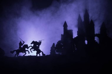 Süvari ve piyade ile ortaçağ savaş sahnesi. Siluetleri şekiller ayrı nesneler olarak mücadele eski Gotik kale ile koyu tonda sisli arka plan savaşçılar arasında