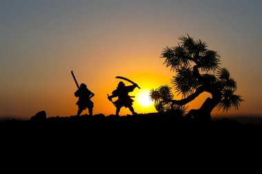 Düelloda tree yakınındaki iki samurais silüeti. İki samurais ve günbatımı gökyüzü ile hayal et. Seçici odak