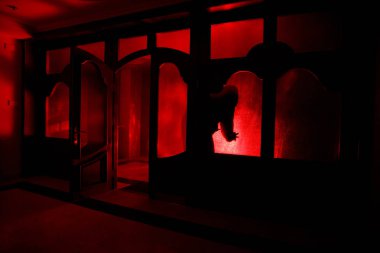 Kapalı cam bir kapıdan geçen, bilinmeyen bir gölge figürünün silueti. Geceleri pencerenin önündeki bir insanın silueti. Manyağın bulanık silueti korkunç cadılar bayramı konsepti.