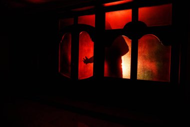 Kapalı cam bir kapıdan geçen, bilinmeyen bir gölge figürünün silueti. Geceleri pencerenin önündeki bir insanın silueti. Manyağın bulanık silueti korkunç cadılar bayramı konsepti.