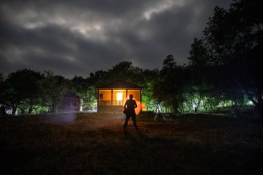Adam gece ormanda silüeti. Işık ile karanlık ormanın içinde duran kişi silüeti. Karanlık gece ormanda. Gerçeküstü gece orman sahne. Korku Cadılar Bayramı kavramı.