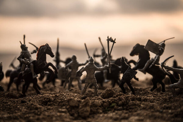 Средневековая боевая сцена с кавалерией и пехотой. Силуэты фигур как отдельные объекты, борьба между воинами на закатном туманном фоне. Селективный фокус
