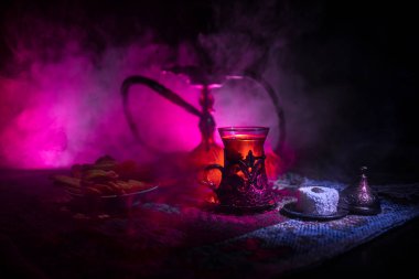 Nargile kömürü nargile kupa Arap iç de buhar bulutları yapma. Şark süsleme halı Doğu çay töreni üzerinde. Şık oryantal shisha içinde karanlık arka ışık ile. Seçici odak